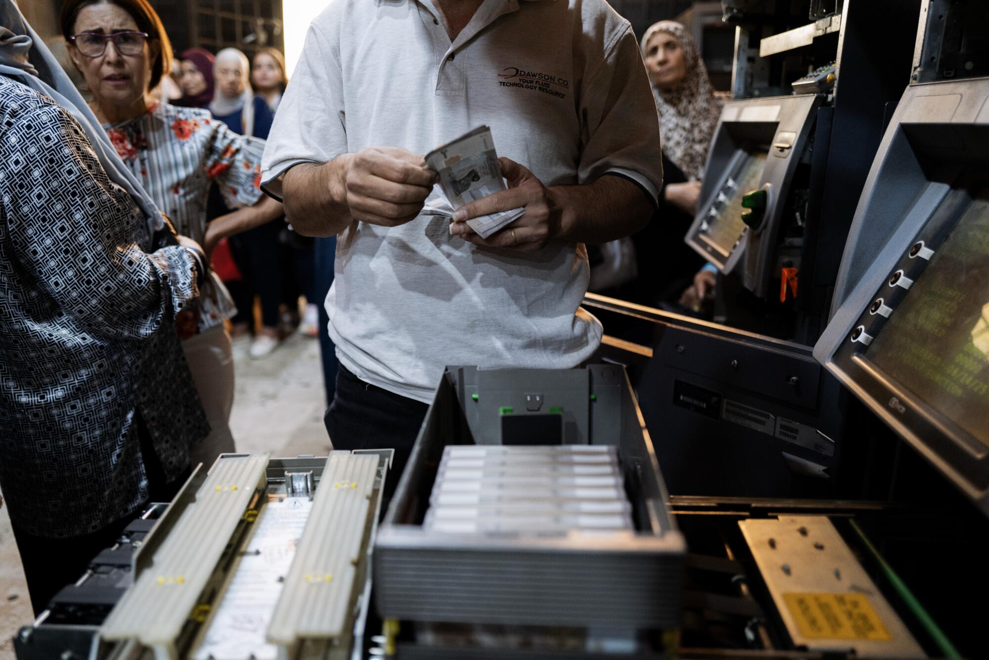 A man reloads an ATM's depleted stock of Syrian pounds in Damascus.