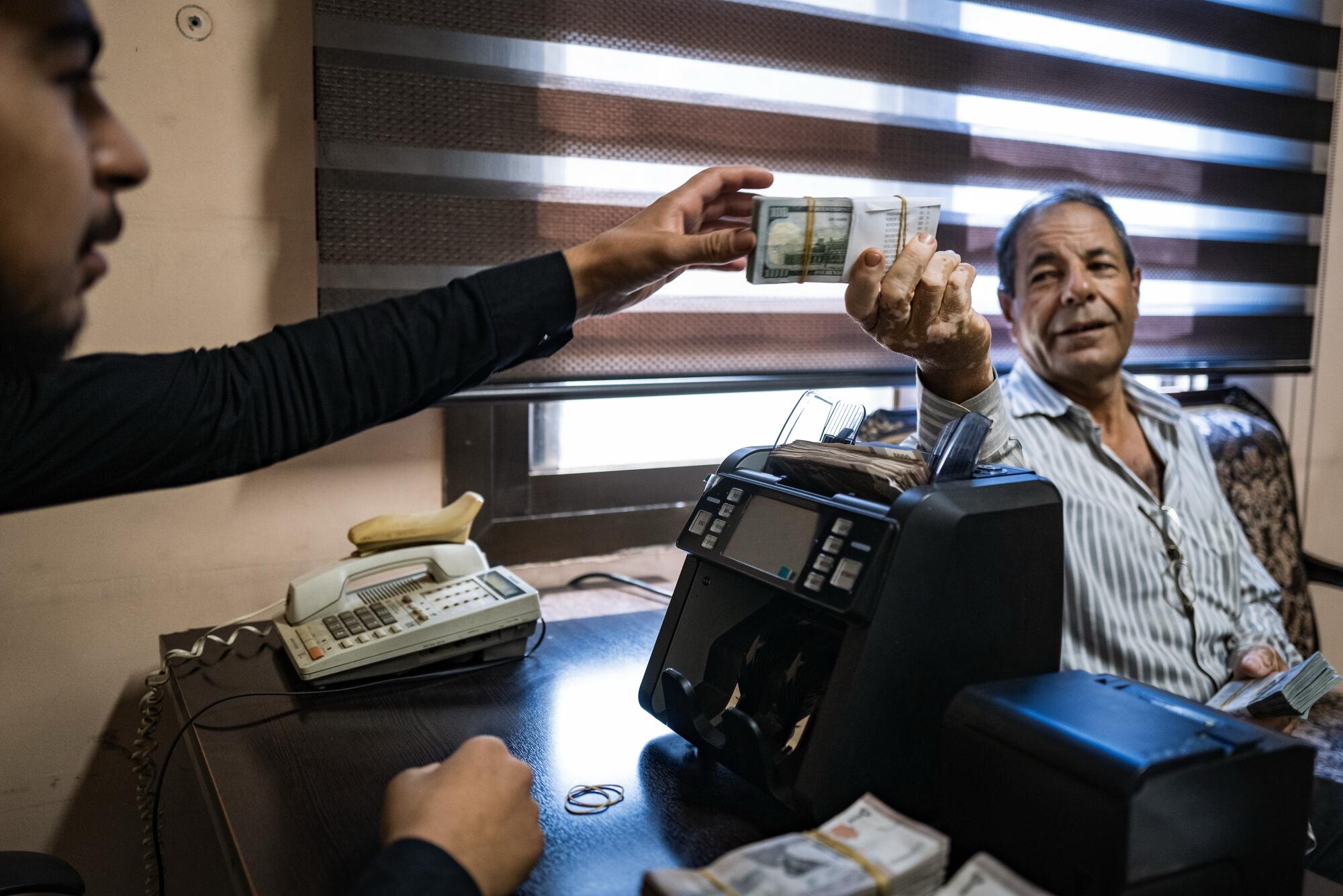 Wads of U.S. dollars are handed to a money collector.