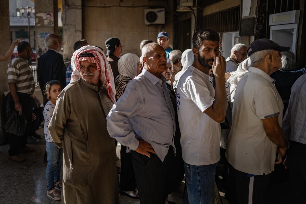 Syrians enter Damascus' Real Estate bank, getting in line to use a functioning ATM.