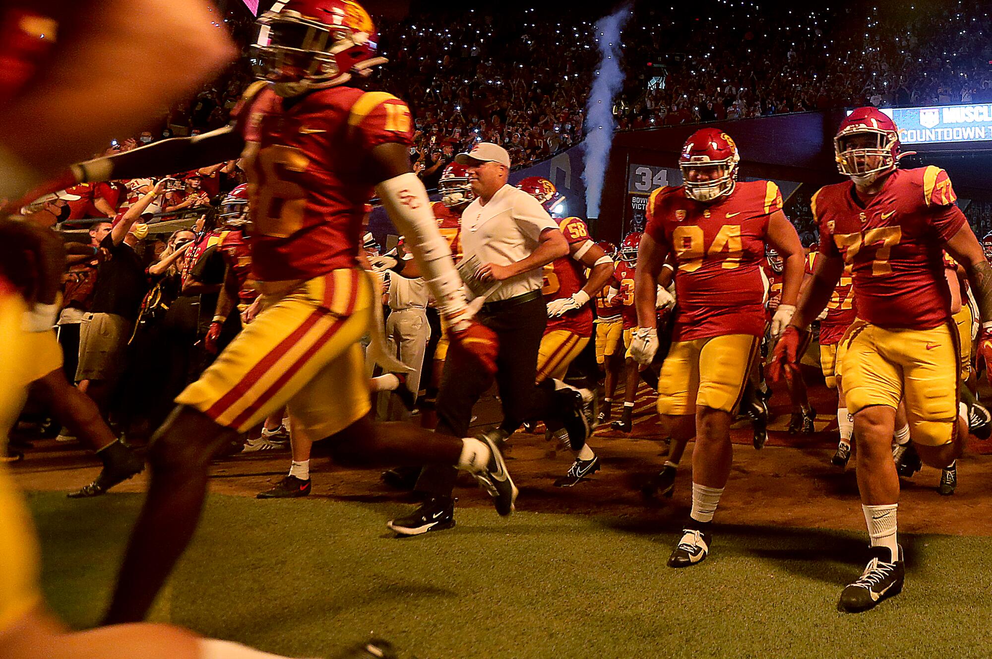 USC coach Clay Helton runs onto the field with his Trojans before facing Stanford at the Coliseum on Sep. 11, 2021.