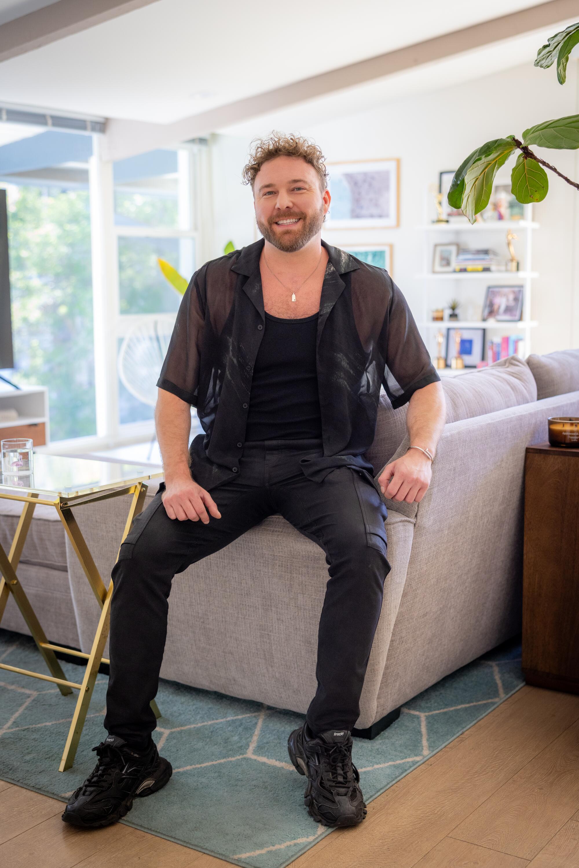 Tyler Pina sets on his sofa in his penthouse apartment.