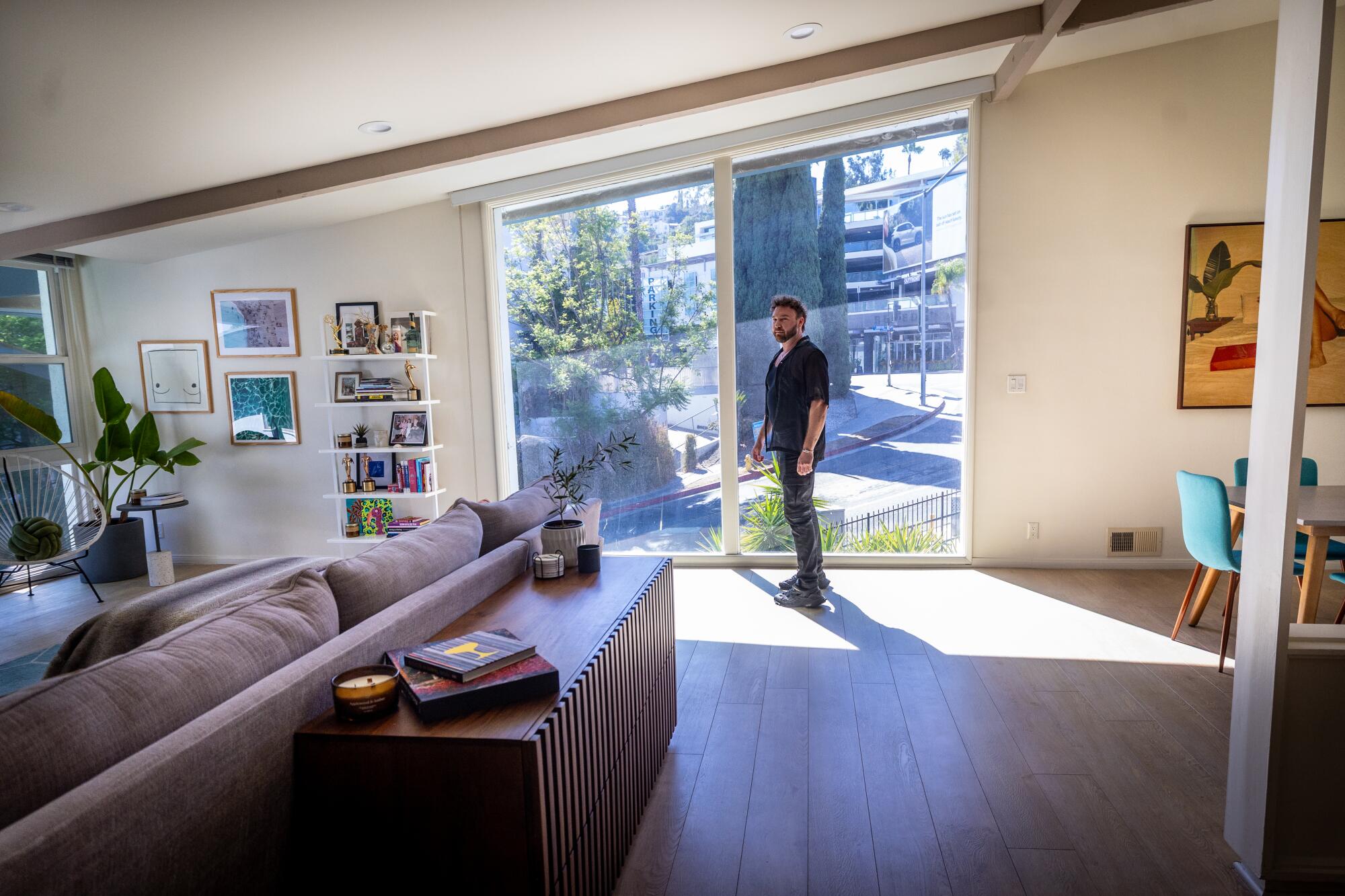 Tyler Pina stand by a large window in penthouse apartment in the Sunset Lanai apartments.