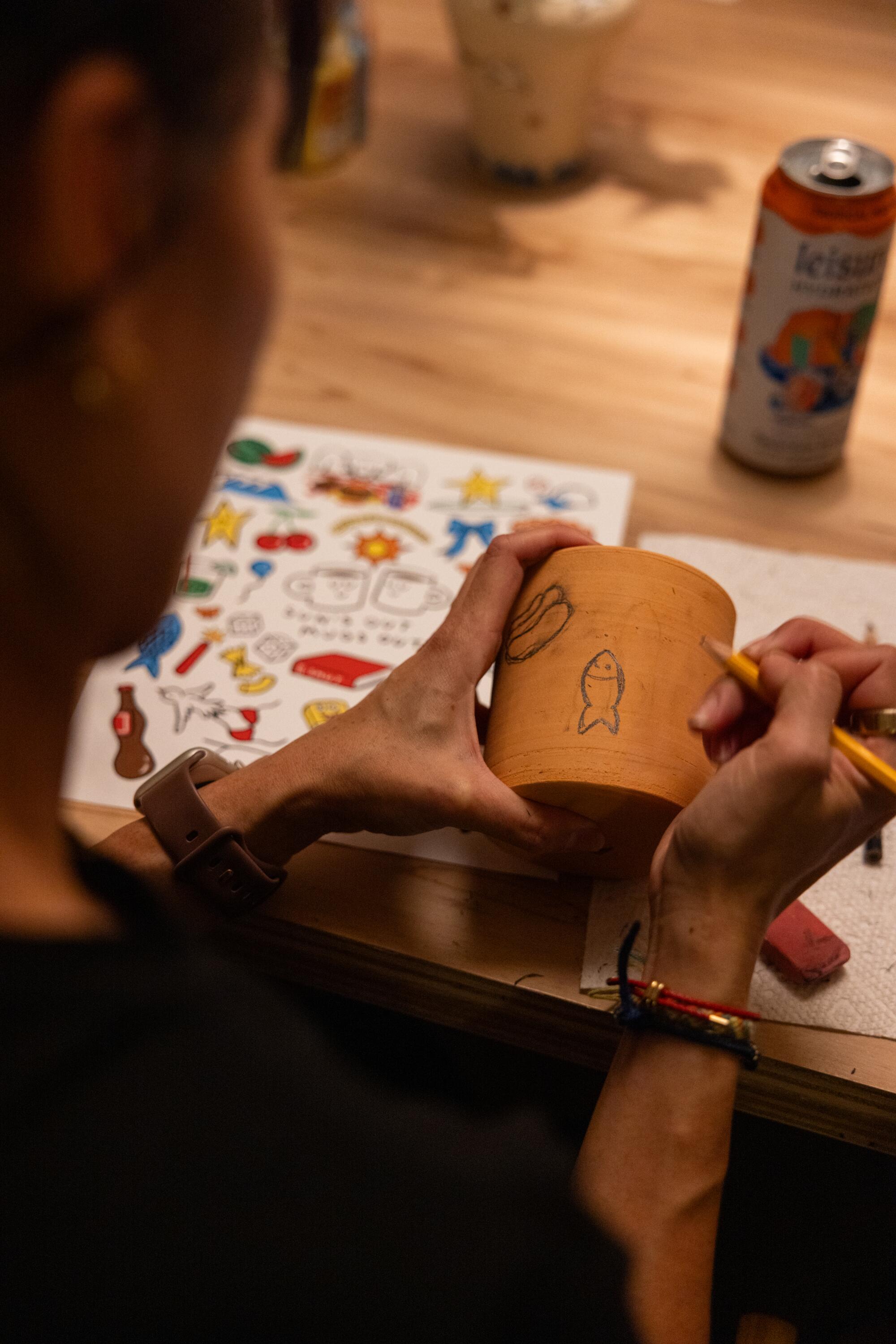 Fiona Chen draws with pencil on her mug.