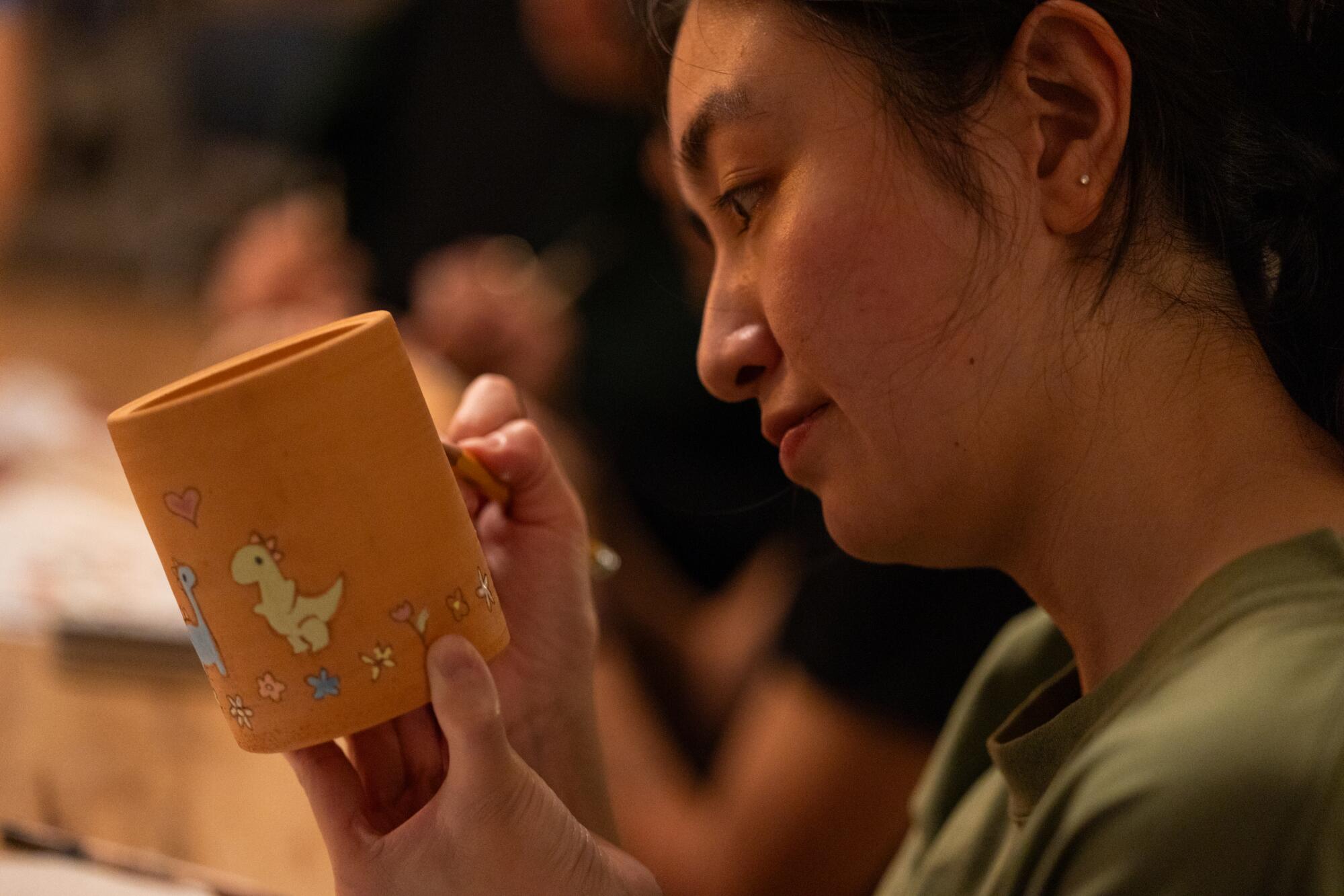 Elaine Chen draws with a pencil on her mug.