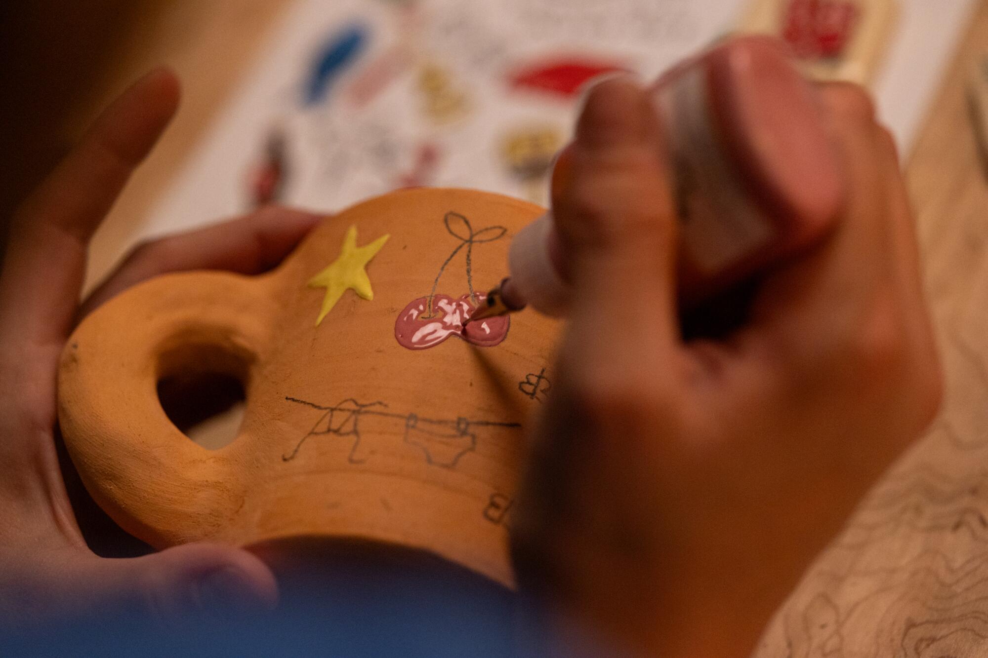 Celine Cormier paints a cherry on her mug.