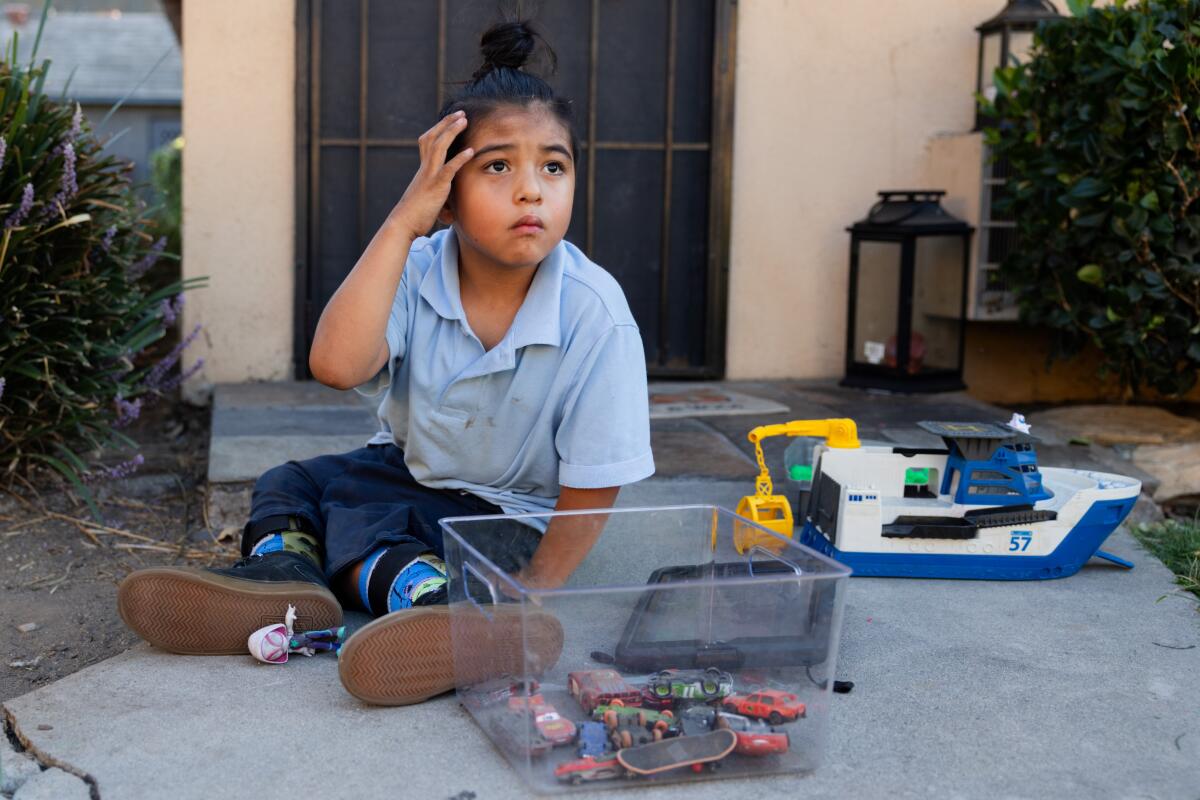 Elijah plays with toy cars outside his aunt's home in Tustin.