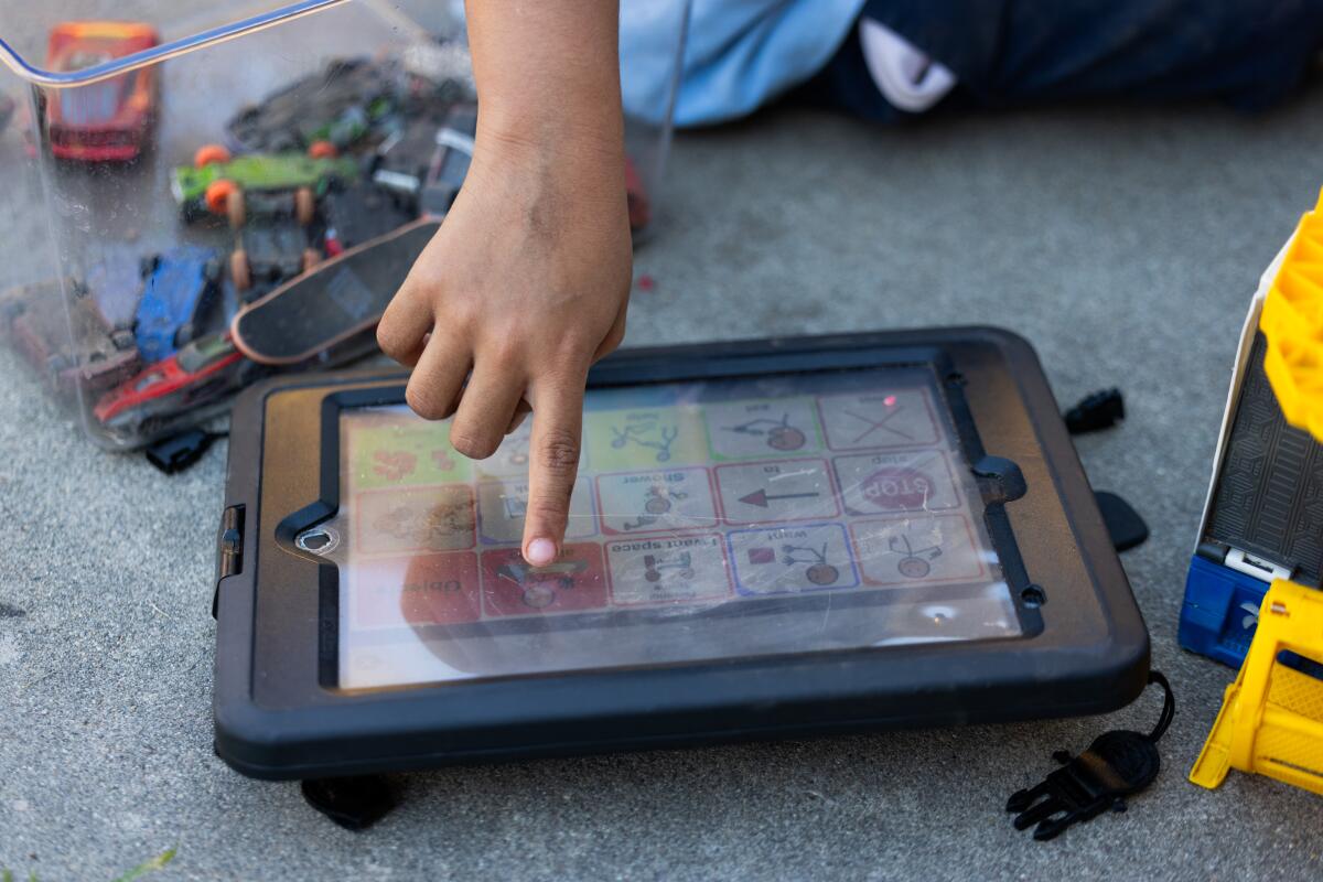 Elijah points to a command on his Proloquo speech app, which he uses to communicate his needs.