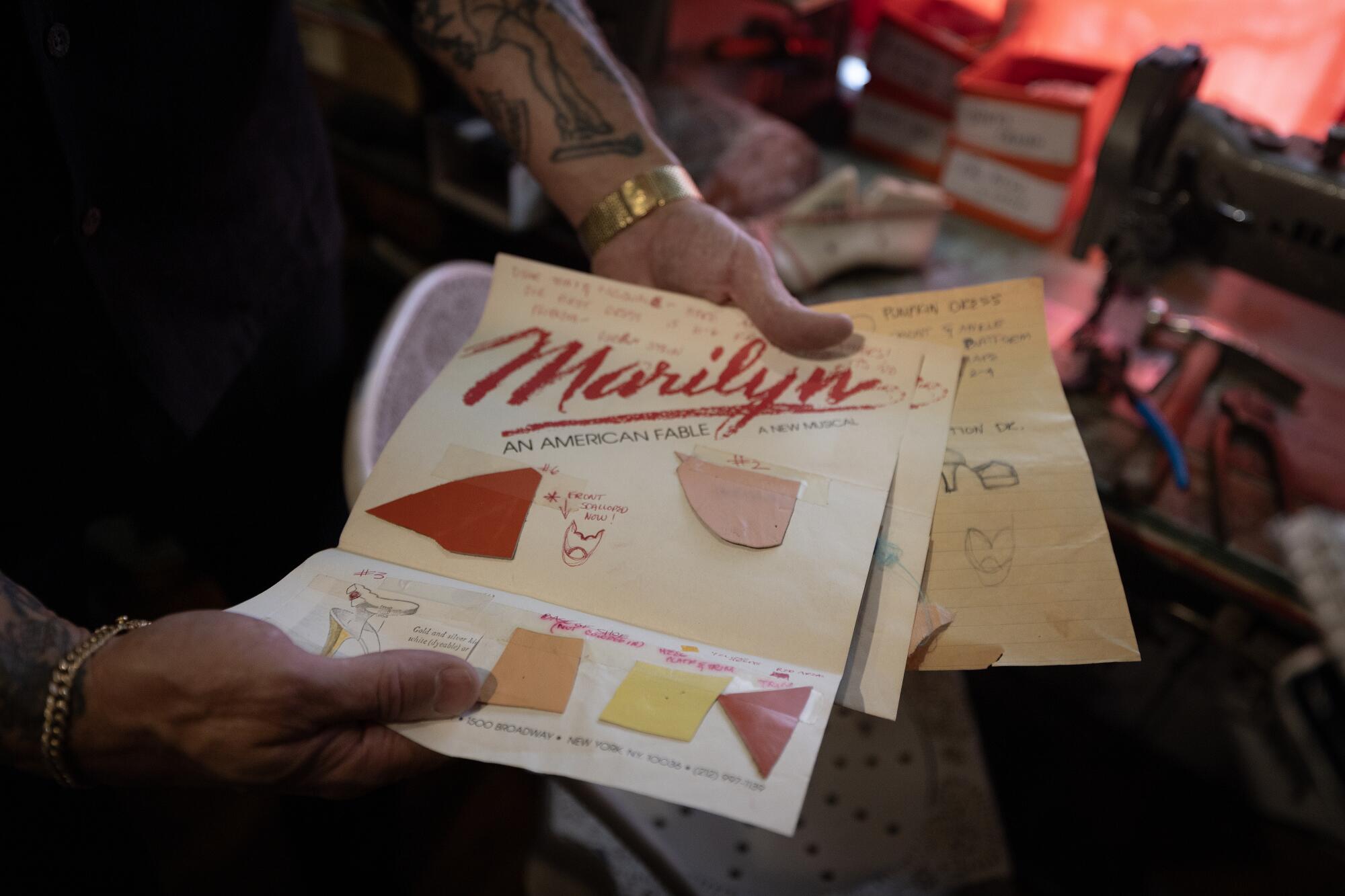 A man holds up a piece of paper with fabric samples on it.