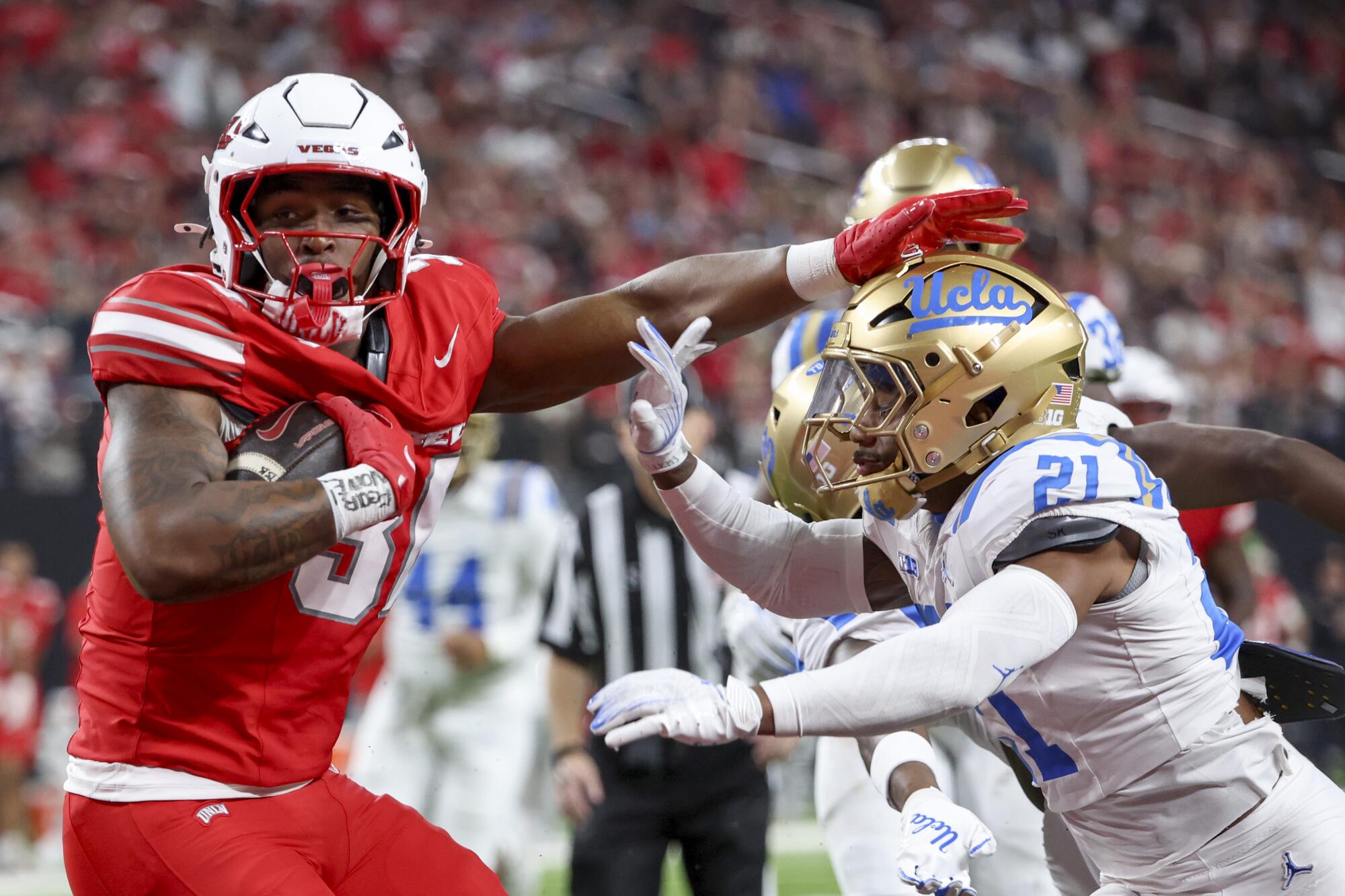 UNLV's Var'Keyes Gumms (30) stiff arms UCLA's Cole Martin (21) while scoring a receiving touchdown at Allegiant Stadium.