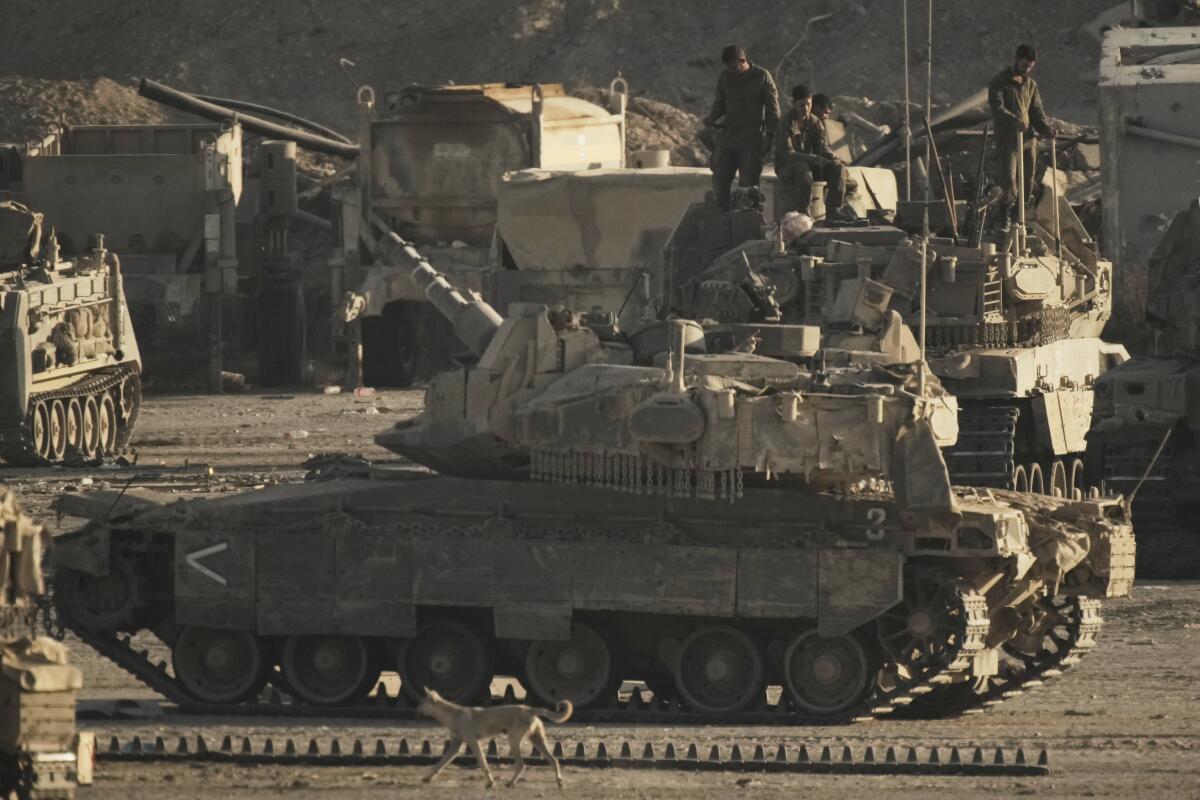 Israeli soldiers work on their tanks and armored personnel carriers at a staging area on the border with the Gaza Strip.