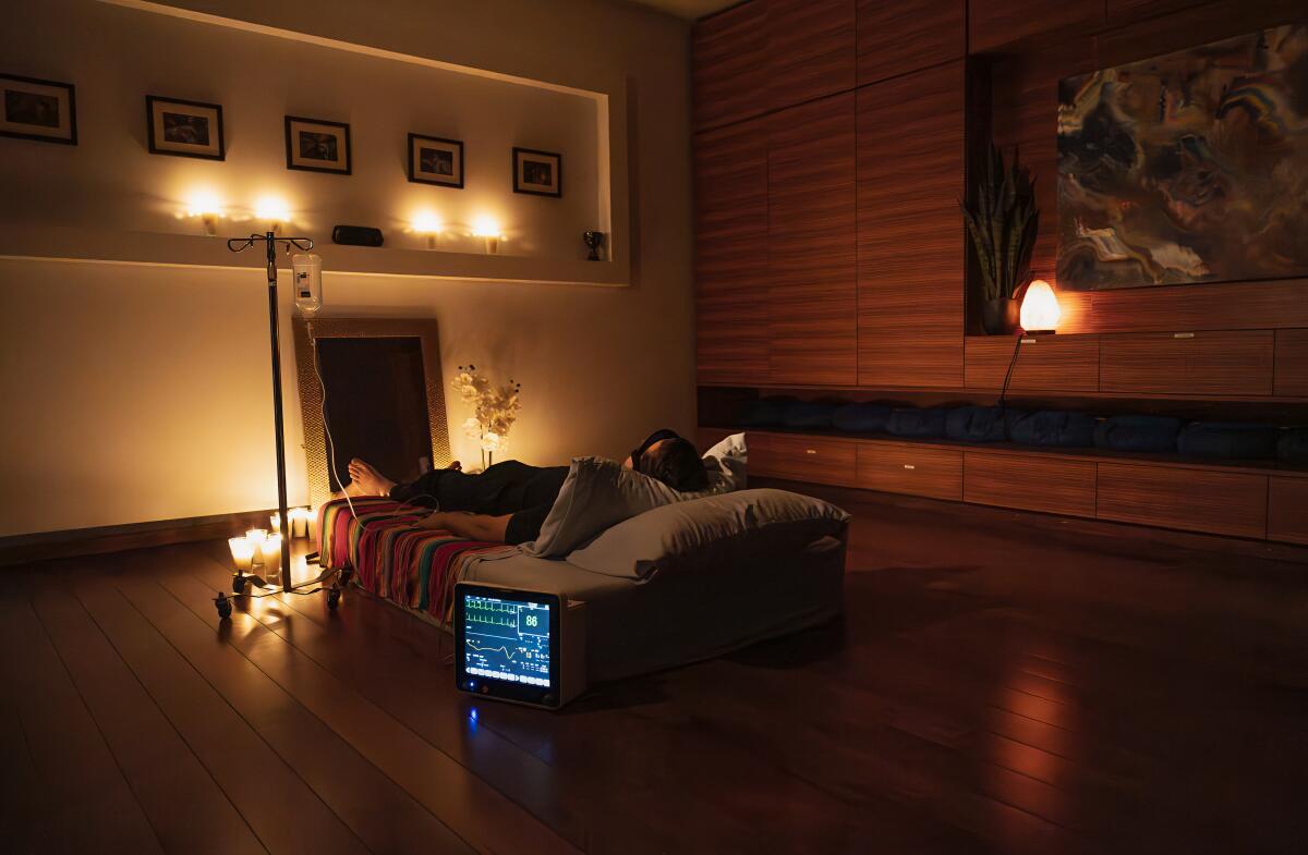 A darkened room with a bed and soft lighting and some medical monitors.