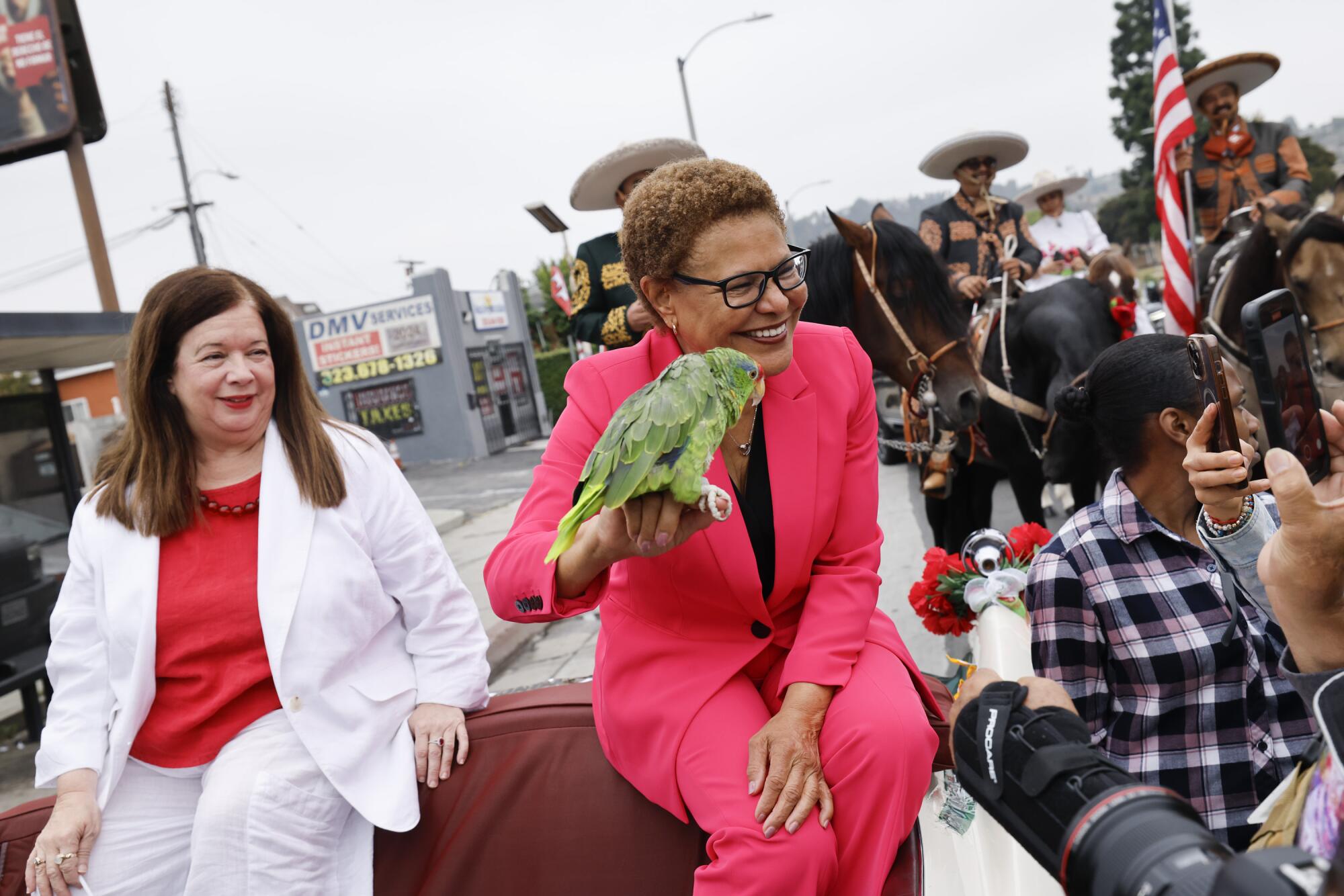 Mayor Karen Bass holds TJ's parrot Pepe Hermon while sitting on a car in the parade.