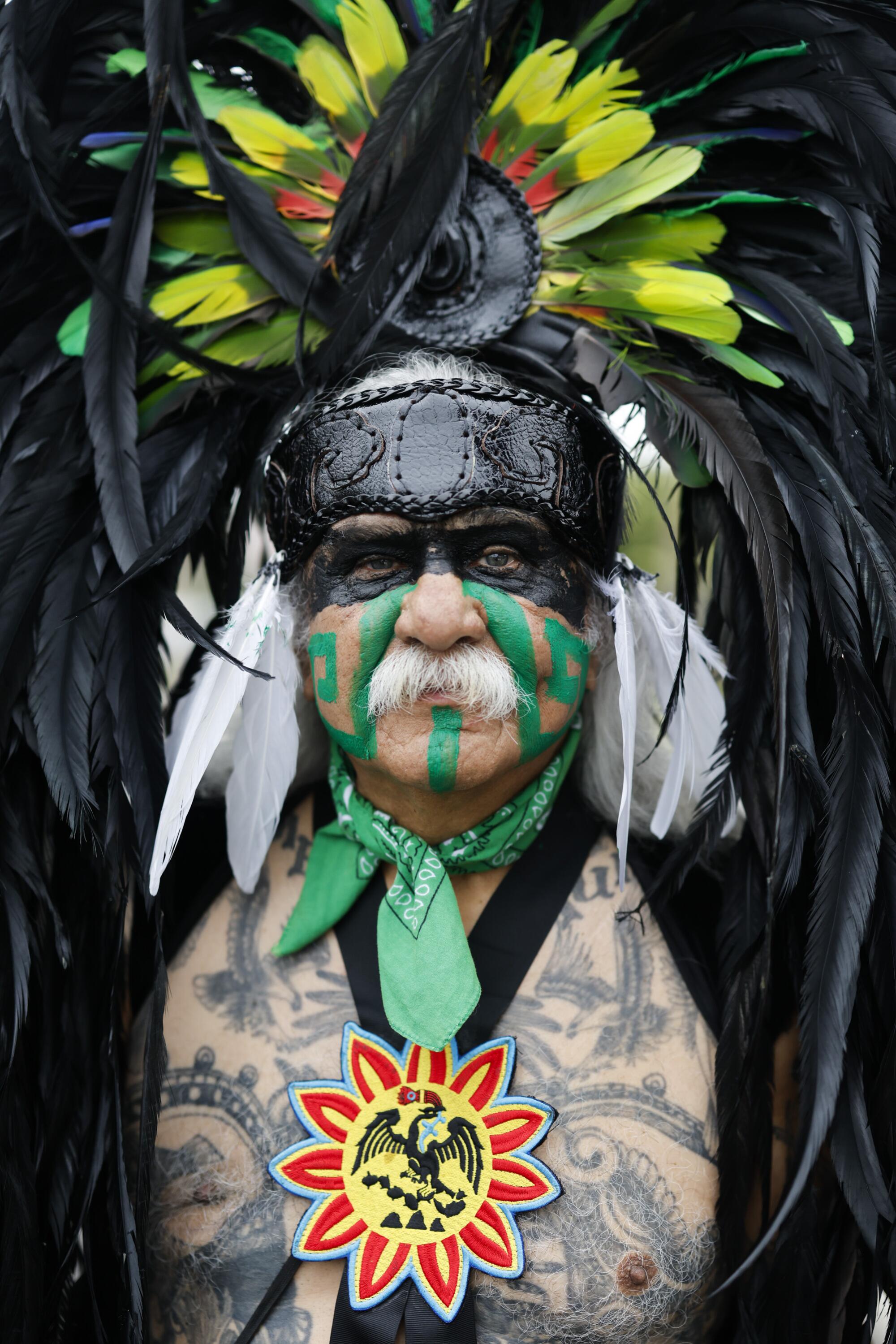 Alfonso Fox Orozco wears traditional Mexican dress of colorful feathers and a sun decoration in his chest at the parade.