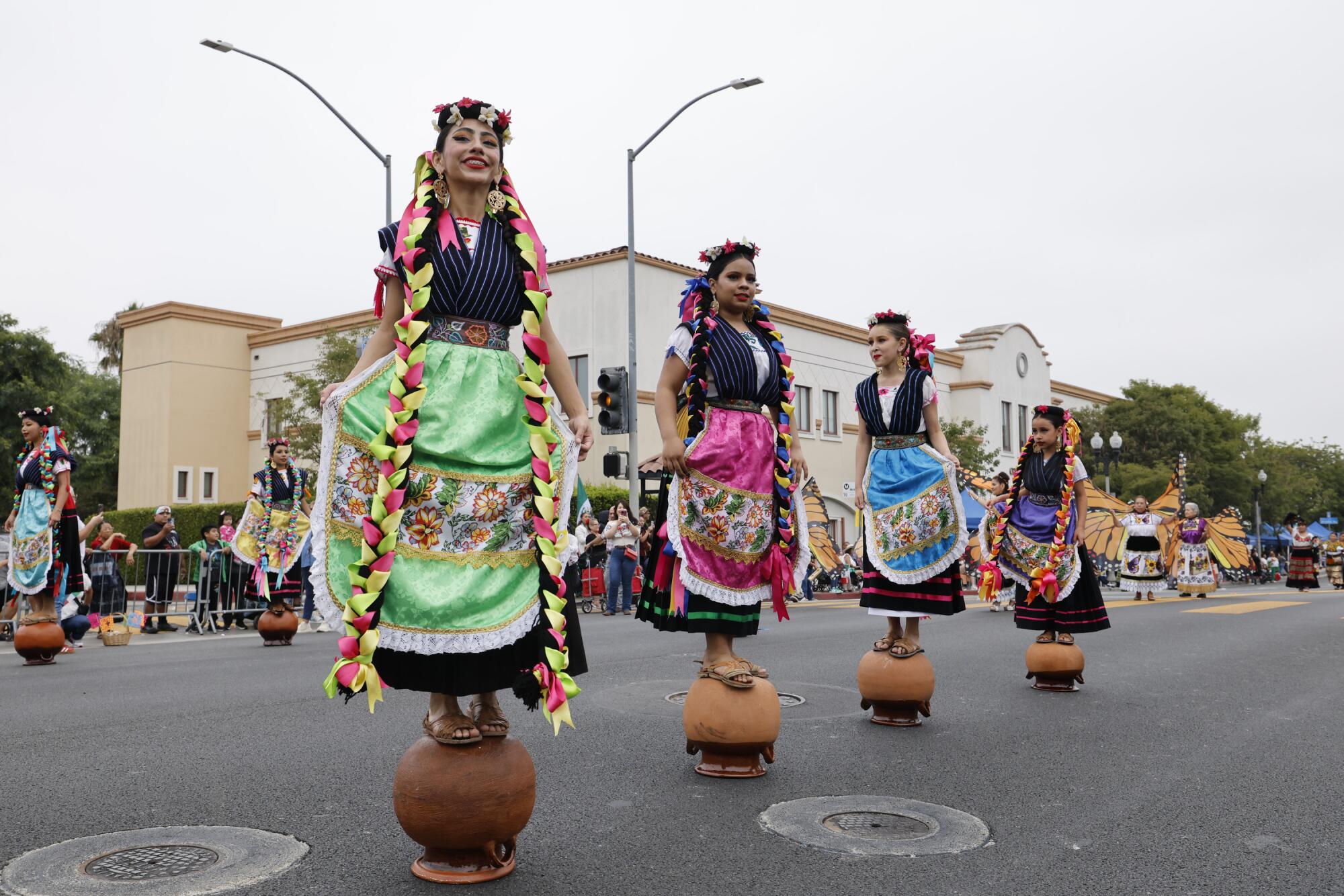 Girls dressed as vendors from Patzcuaro, Michoacan, balance on pots on the street.