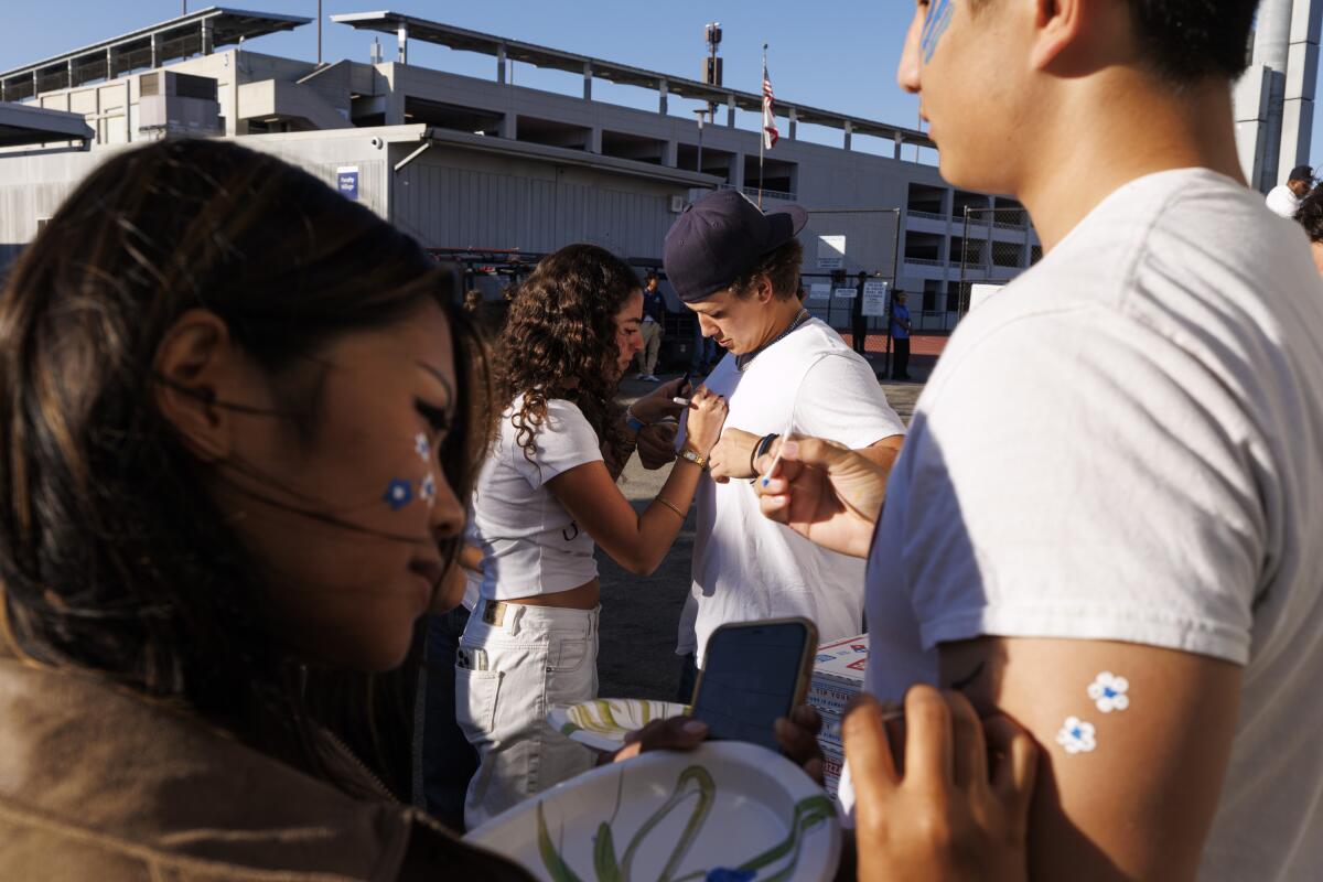 Pali High senior Alessandra Santini , center, decorates junior Hudson Ramberg's shirt before the football game