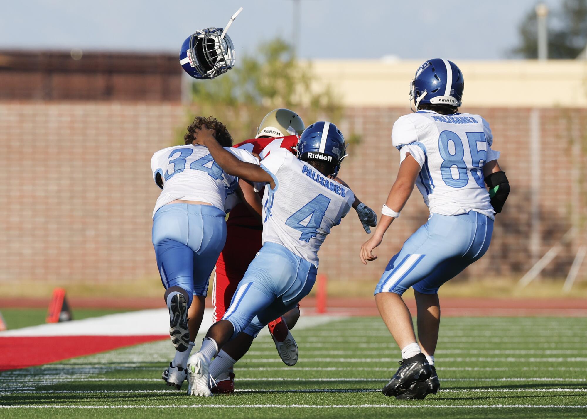 Pali High freshman defender Hudson Roth's (34) helmet flies off while attempting to tackle a Taft High player.