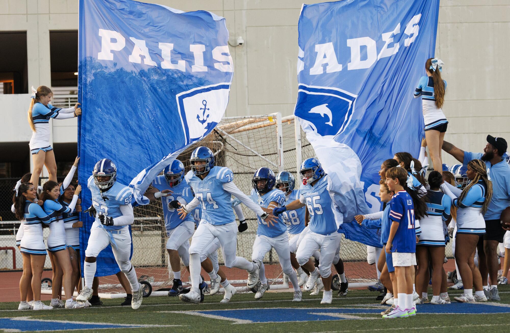 Pali High football players burst through their school banner before the game against Granada Hills Charter High School.