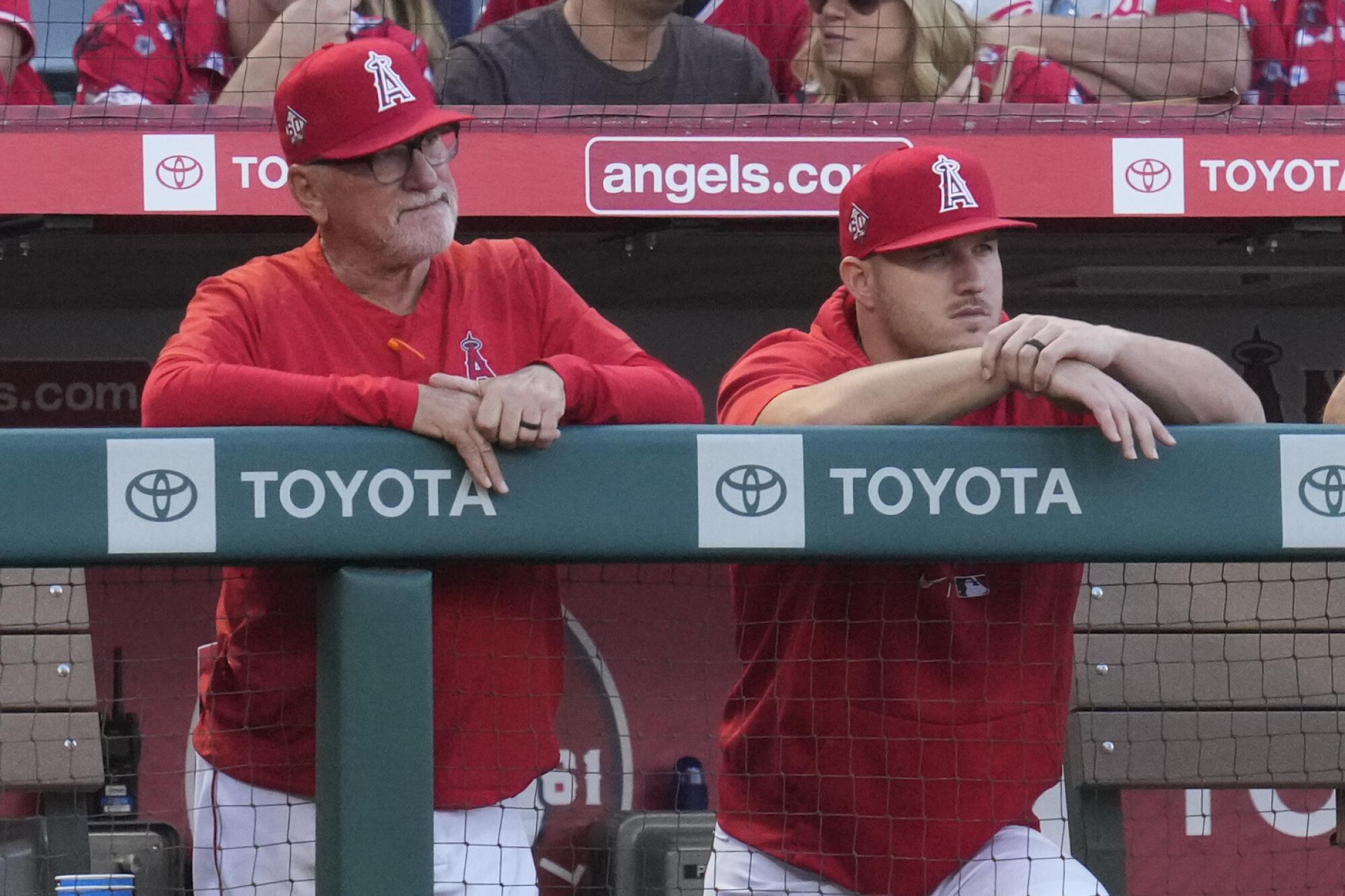 Angels manager Joe Maddon, left, and Mike Trout stand in the dugout during a game against the Orioles in July 2021.