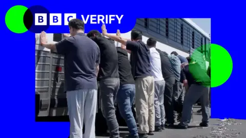 EPA A still frame from a video shows a group of men, with their backs to the camera and hands on the side of a white coach with black bars on its windows during an immigration raid at the Hyundai-LG vehicle assembly plant in Ellabell, Georgia. The men are in casual clothing, mostly jeans or slacks and T-shirts.