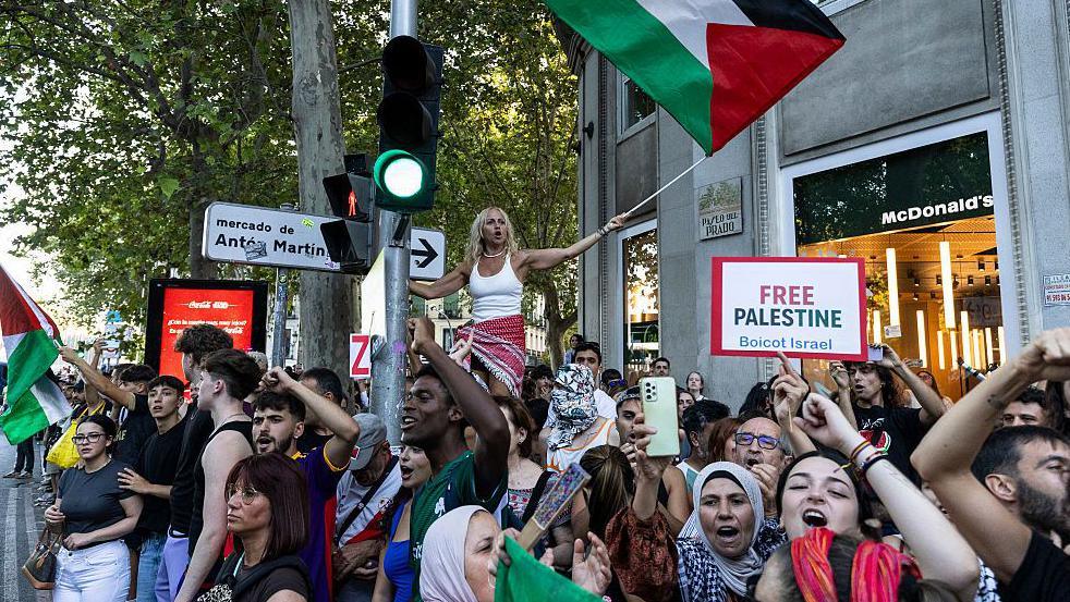 Pro-Palestinian protesters in a group with a flag and placard during the final Vuelta a Espana stage in Madrid