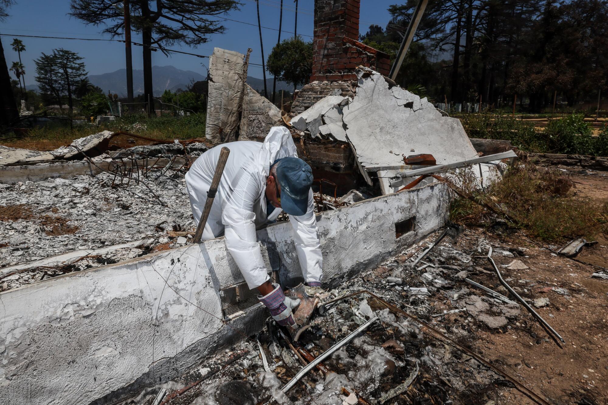 Stanley C. Wilson sifts through the ashes that remain of John Outterbridge's family home.