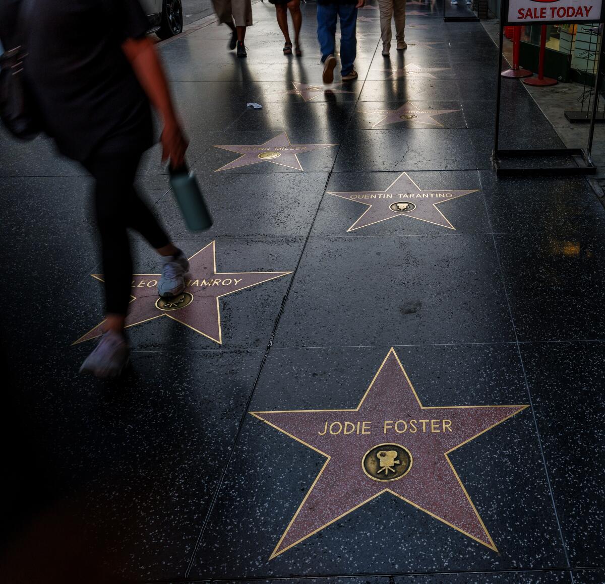 Tourists walk across celebrity stars on Hollywood Boulevard in front of the Dolby Theater.