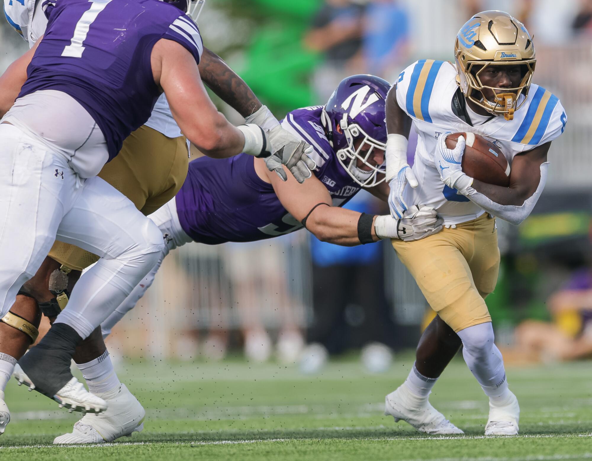UCLA's Anthony Woods carries the ball as Northwestern's Aidan Hubbard tries to tackle him during the first half Saturday.